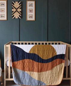 a baby crib with a quilt on it and pictures above the crib,