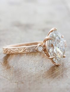 an old - fashioned engagement ring with a diamond in the center on a wooden surface