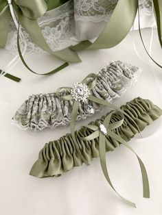 two garters are laying next to each other on a white surface with green ribbons