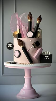 a pink cake with makeup and brushes on it