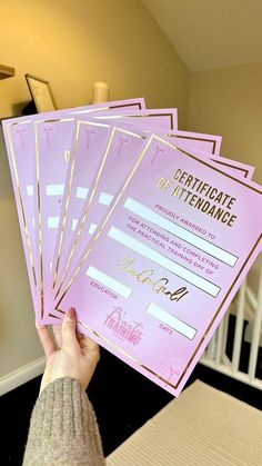 a person holding five pink and gold certificates