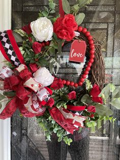 a wreath with red and white flowers is hanging on the front door to say love