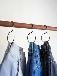 three pairs of jeans hanging on a wooden rail