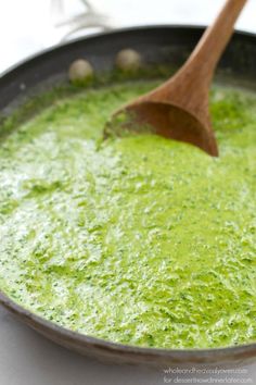 a pan filled with green liquid and a wooden spoon