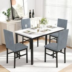 a dining table with four chairs and a white rug on the floor in front of it