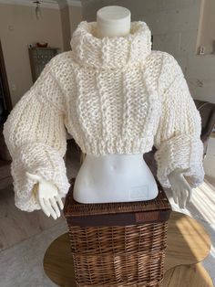 a mannequin wearing a white sweater and hat on top of a wicker basket