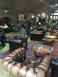 a room filled with lots of leather furniture and motorcycles parked in front of windows on the wall