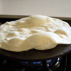 an uncooked pizza dough sitting on top of a wooden stovetop oven burner