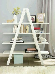 a white book shelf with books on it in front of a window and a rug