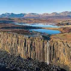 an aerial view of a large waterfall in the middle of a field with mountains and lakes