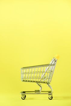 an empty shopping cart sitting in front of a yellow background with the bottom half down