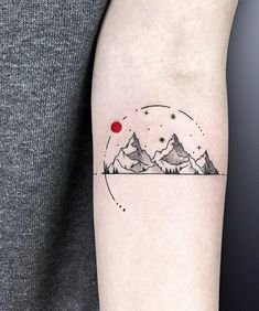 a person with a tattoo on their arm that has mountains and a red dot in the middle