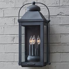 two candles are lit on an outdoor wall light