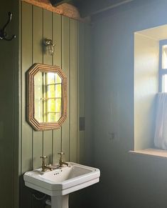 a white sink sitting under a bathroom mirror next to a wall mounted faucet