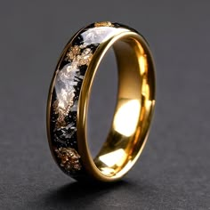 a gold ring with black and white marble inlays on the inside of it