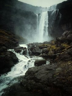 a large waterfall is in the middle of some rocks