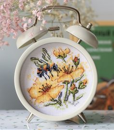 a white alarm clock sitting on top of a table next to a vase filled with flowers