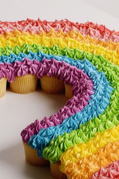 there is a rainbow cake with icing on the top and one cupcake in the middle