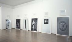 an art gallery with black and white pictures on the wall, framed by metal doors