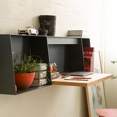 a shelf with two plants on it next to a red chair