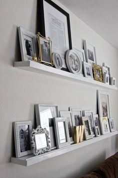 two white shelves filled with pictures and framed photos on top of each other next to a couch