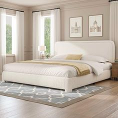 a white bed sitting on top of a hard wood floor next to two large windows