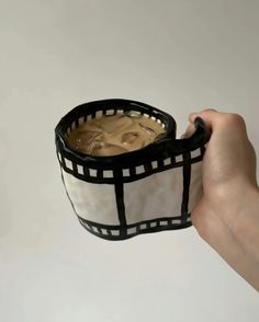 a hand holding a black and white cup filled with liquid in it's sleeve