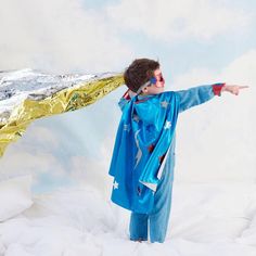 a young boy dressed in blue is pointing at something that looks like a gold foil mountain