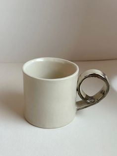 a white coffee cup with a silver ring on it