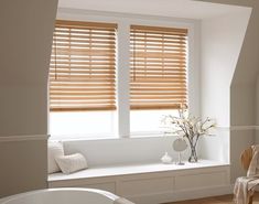 a bathroom with a tub, window seat and wooden blinds on the windowsills