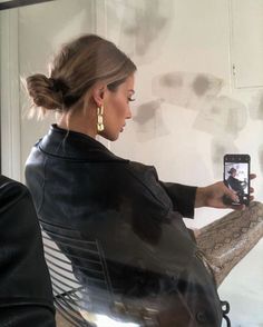 a woman is taking a selfie with her cell phone while sitting in a chair