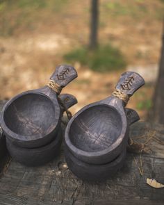 two wooden spoons sitting on top of a piece of wood with writing on them