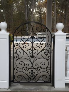 an iron gate is open on the front porch with white pillars and columns around it