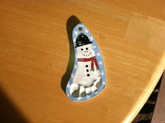 a ceramic snowman ornament sitting on top of a wooden table