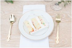 a piece of cake sitting on top of a white plate next to two gold forks