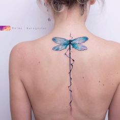 the back of a woman's neck with a dragonfly tattoo on it