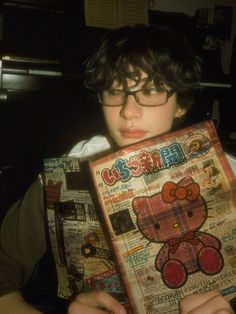 a young boy holding up a book with an image of a teddy bear on it