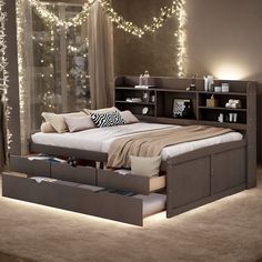 a bed that has drawers underneath it in a room with lights on the wall behind it