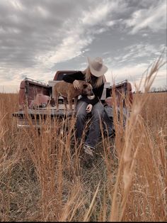 a person sitting in the back of a truck with a dog