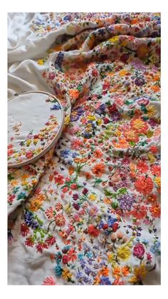 a white bed with colorful flowers on it and a wooden tray sitting on top of it