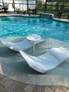 two lounge chairs sitting in the middle of a swimming pool