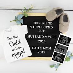 a baby announcement is shown with shoes, socks and t - shirt on the table