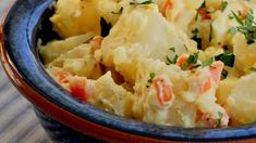 a blue bowl filled with potato salad on top of a table