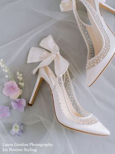 a pair of white high heel shoes next to flowers