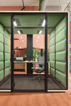 an office cubicle with green walls and glass doors that open up to the outside