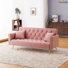 a pink couch sitting on top of a wooden floor next to a white rug in a living room