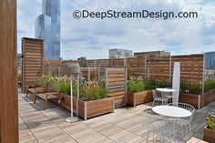 a rooftop garden with wooden planters and tables on the top floor, in front of a cityscape