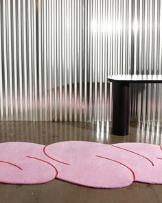 three pink rugs sitting on the floor in front of a table