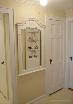 an empty room with two white doors and a shelf on the wall next to it