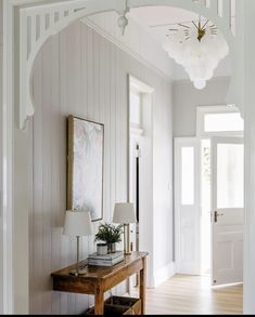 an entry way with a table and lamp next to the entrance door, along with a painting on the wall